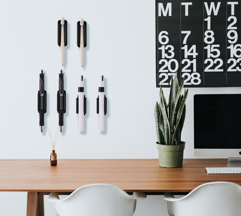 Laad afbeelding in Galerijviewer, Een minimalistische werkplek met een iMac, een kalender aan de muur, Verleidelijke siliconen penhouders op het bureau, een potplant en twee stoelen.
