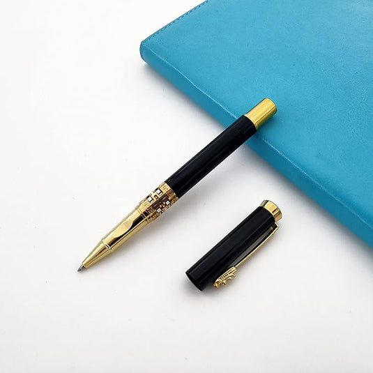 Een klassieke metalen rollerball voor een luxe schrijfervaring met zijn dop ernaast, liggen naast een gesloten blauw notitieboek op een wit oppervlak.