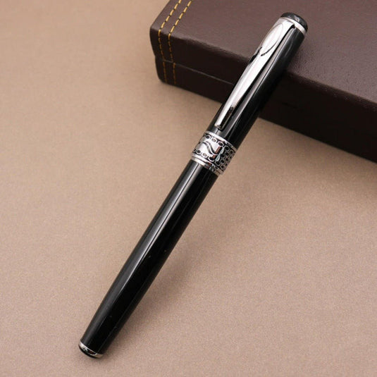Een elegante Ervaar de tijdloze elegantie - Metalen pen cadeau voor stijlvol schrijfplezier rust op een bruin oppervlak naast een gesloten boek en belooft een luxe schrijfervaring.