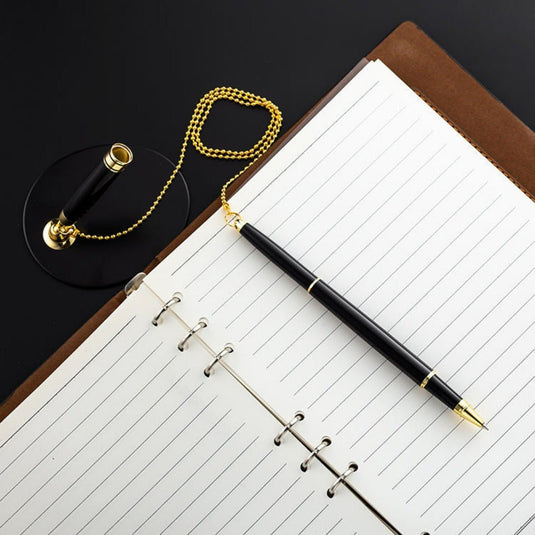 Een open notitieboekje met een zwarte en gouden pen op een georganiseerde metalen bureaustandaard.