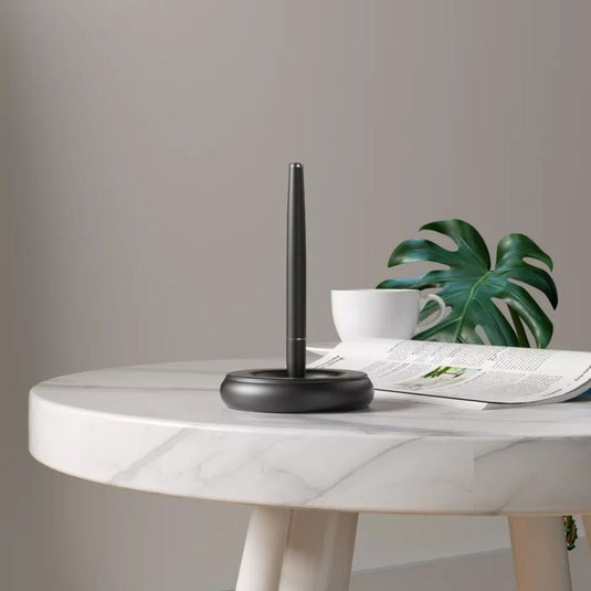 Modern en minimalistisch ontwerp bureau met een Houd uw bureau netjes met de magnetische pen standaard, koffiekop en open tijdschrift naast een potplant.