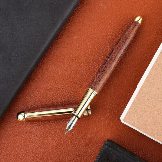 Een elegante Ervaar de warmte van ambachtelijk schrijven met een fijn punt ligt op een bruine leren ondergrond naast een gesloten notitieboek.