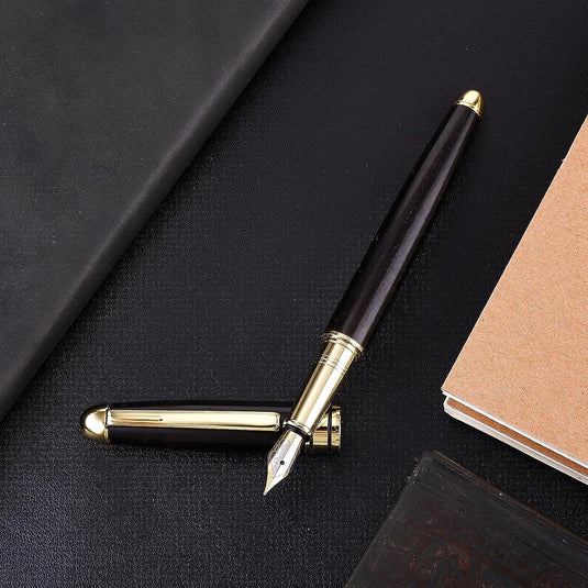 Elegant Ervaar de warmte van ambachtelijk schrijven met een gouden fijne punt naast een gesloten notitieboek op een donker oppervlak.