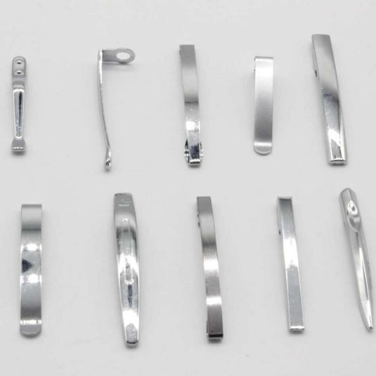 Een assortiment metalen nagelknippers en onderdelen, waaronder Nooit meer uw pen kwijtraken met deze set van 10 metalen penclips, neergelegd op een grijze achtergrond.