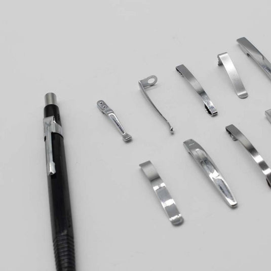 Een duurzame Nooit meer uw pen kwijtraken met deze set van 10 metalen penclips naast de gedemonteerde interne metalen componenten op een grijze achtergrond.