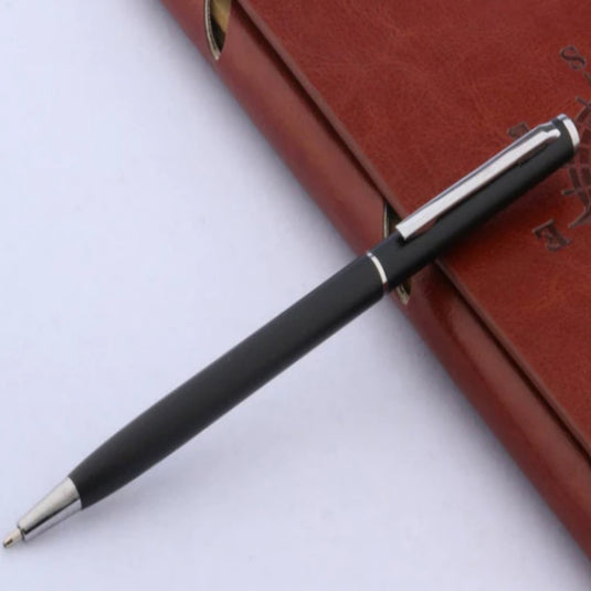 Ontdek de tijdloze elegantie van klassieke balpennen rustend op een gesloten bruin notitieboek.