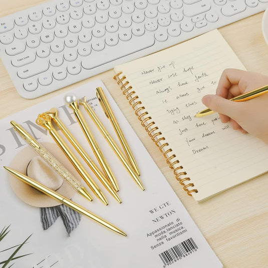 Een persoon die in een notitieboekje schrijft met Schattige pennen voor dames: 8 betoverende penjuweeltjes die uw creativiteit vleugels geven op een bureau naast een computertoetsenbord en muis.