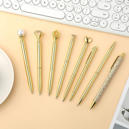 Een assortiment van verrassende pennen voor dames en stylussen in goudkleur, daarnaast een toetsenbord op een lichtgekleurde opp