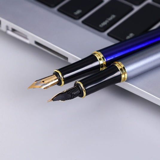 Close-up van een persoonlijk cadeau: de Schrijf in stijl met de metalen messing vulpen en een balpen rustend op een laptop-toetsenbord.