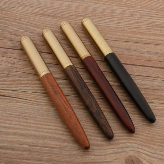 Vier Bend Nib pennen met koperen doppen en unieke schrijfervaring, gelegen in een rij op een houten oppervlak.