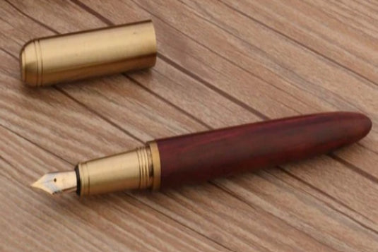 Een duurzame Schrijf in stijl met onze unieke houten en koperen pen met een houten houder en metalen dop, voorzien van een F-punt, geplaatst op een houten oppervlak.