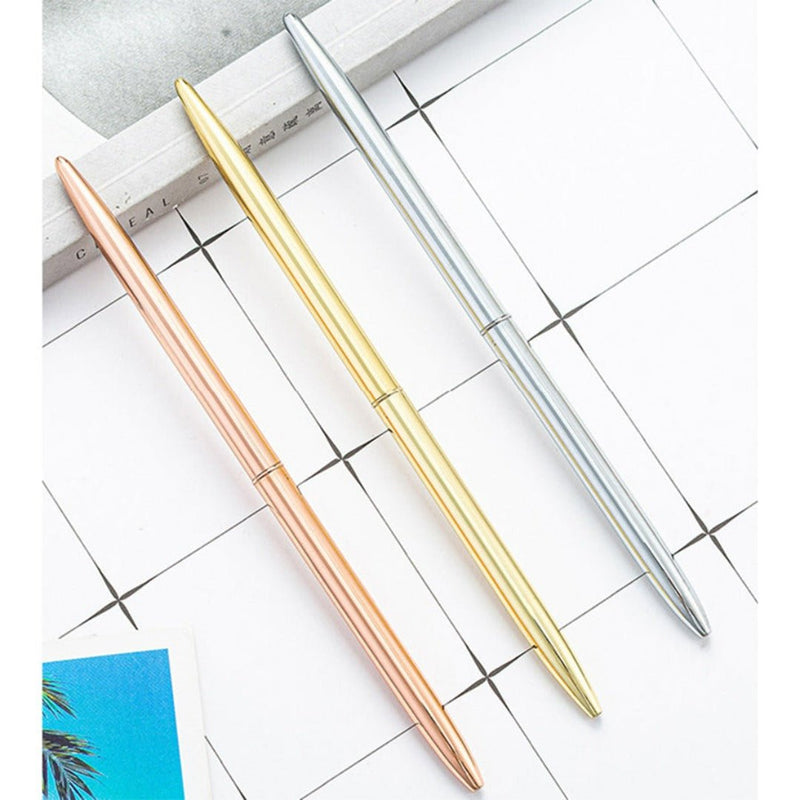Laad afbeelding in Galerijviewer, Drie elegante zakelijke metalen balpennen in roze goud, goud en zilveren kleuren, georganiseerd diagonaal over een planner met een rasterontwerp.
