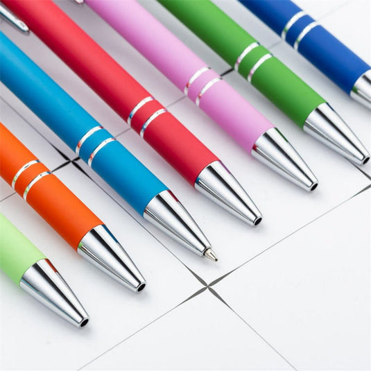 Schrijf uw gedachten op met comfort en stijl met onze Kleurrijke klikbalpennenset op een rij gerangschikt op een rasterpapierachtergrond!