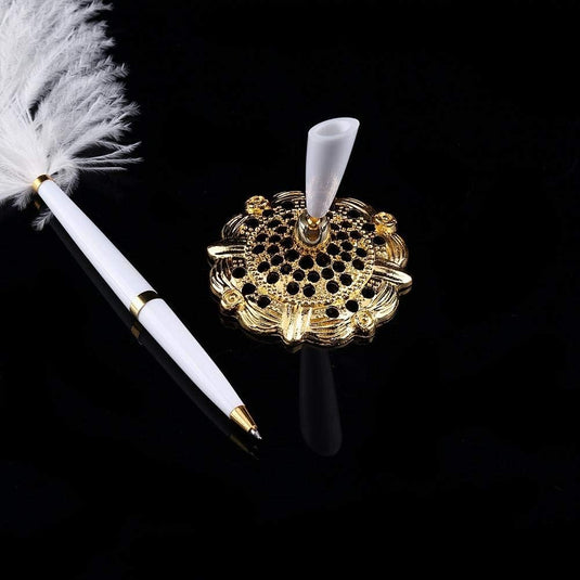 Een elegante witte en gouden Verleid uw zinnen met de struisvogelveren schrijfpen naast een sierlijke metalen houder met een veer op een zwarte achtergrond.
