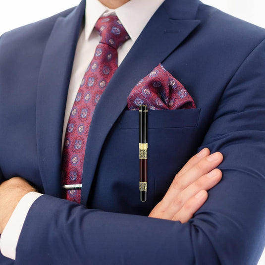 Goedgeklede man in een marineblauw pak met een rode stropdas met patroon en bijpassend pochet, met een Verleidelijke luxe balpen in zijn hand: Schrijf met stijl en precisie.